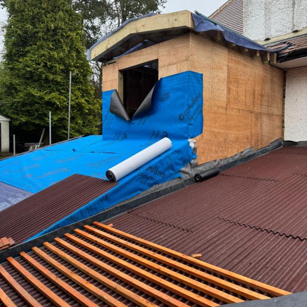 View on a roof with installed Isoline sheets and clay tiles to be installed. Extension of residential house